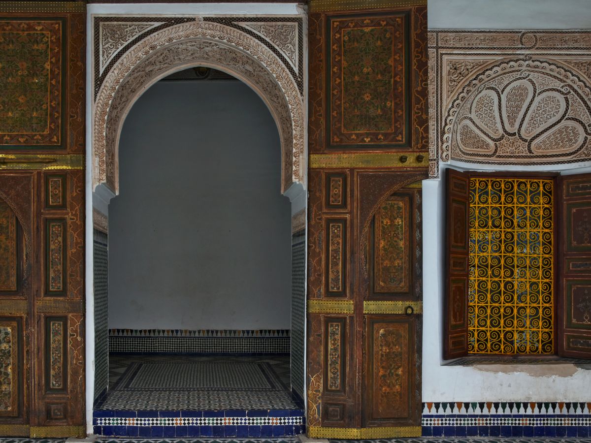 A carved cedar door opening onto a tiled courtyard